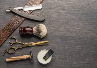 Ahşap arka planda klasik kuaför ve kuaför aletleri. Koyu renk ahşap masada duran berber dükkanının enstrümanlarının üst görüntüsü.