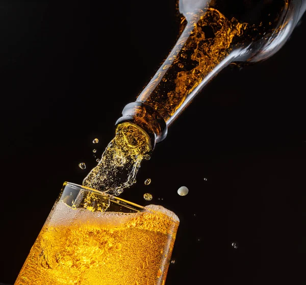 啤酒从瓶子里喷出 倒入啤酒杯 造成大量气泡和泡沫 深褐色背景 — 图库照片