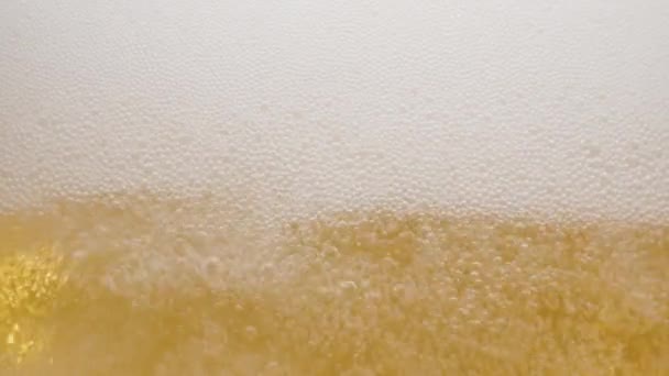 对一杯啤酒的内容进行特写 啤酒慢慢地倒入杯子里 造成大量的气泡 波浪和泡沫 — 图库视频影像