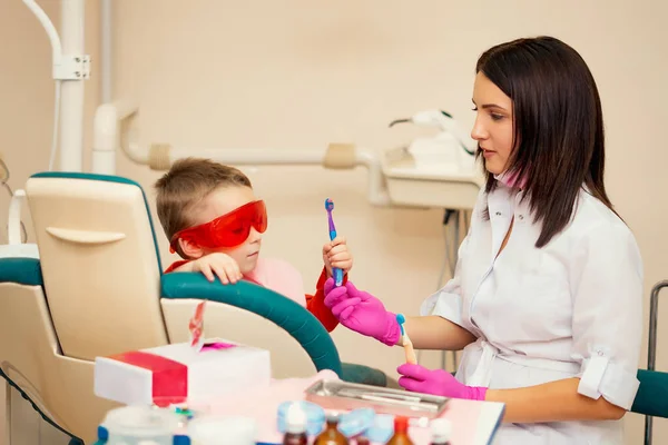 Kleines Kind beim Zähneputzen Der Zahnarzt im Büro sitzt mit den Kindern und bringt ihnen bei, wie man die Zähne putzt, Kinder sind glücklich — Stockfoto