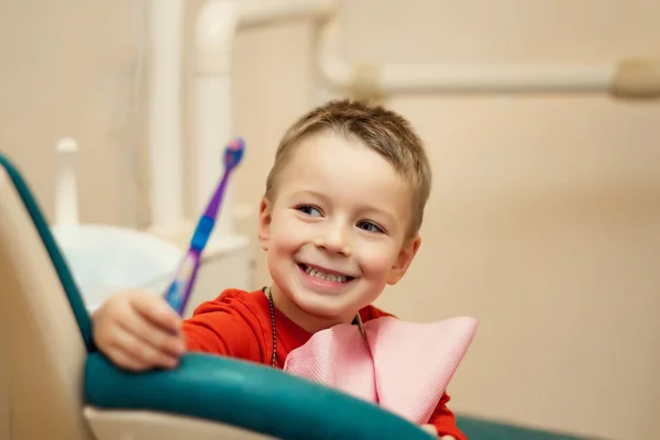 Petit enfant pendant le brossage de ses dents le dentiste au bureau s'assoit avec les enfants et leur apprend à se brosser les dents, les enfants sont heureux — Photo
