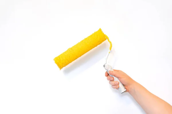 白い背景に黄色の塗装ローラーで手を隔離し 家の修理 — ストック写真