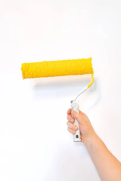 白い背景に黄色の塗装ローラーで手を隔離し 家の修理 — ストック写真