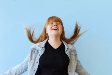 Doğum günü, Sevgililer Günü konsepti. Mavi arka planda bir buket altın renkli balon tutan mutlu, kızıl saçlı kız mutlu.