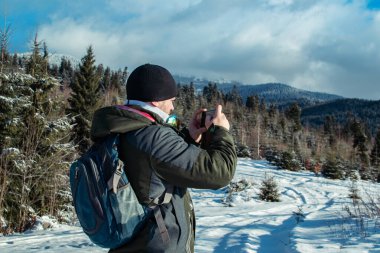 Sakallı, kışlık kıyafetler giyen telefonda konuşan bir adam. Bir yürüyüşçü sırt çantasıyla kış dağlarına gider. Kışın güzel dağlar