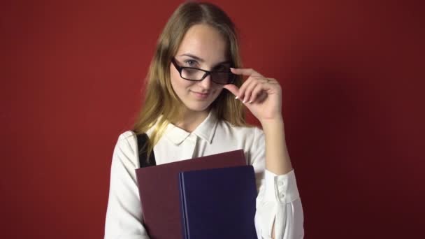 Aantrekkelijke Student blond meisje met bril op rood — Stockvideo