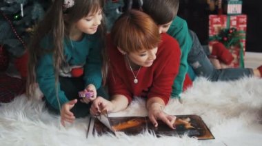 Noel ağacı yakınındaki aile kitap okuma