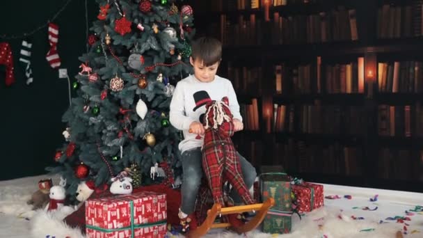Хлопчик розважається з дерев'яною іграшкою коня — стокове відео