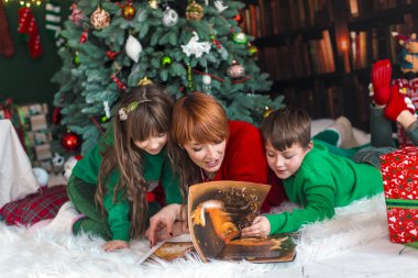 Noel ağacı yakınındaki aile kitap okuma
