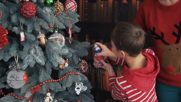 Αγόρι που κάνουν τεχνητό χιόνι χριστουγεννιάτικο δέντρο — Αρχείο Βίντεο