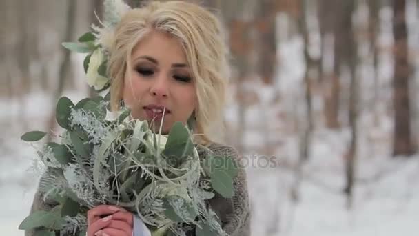 Belle fille blonde tenant un bouquet dans la forêt d'hiver — Video