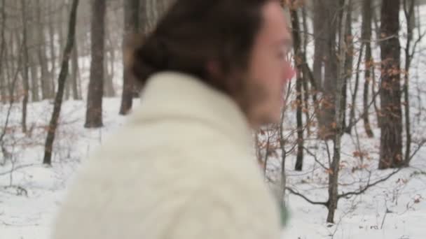 Portret uśmiechający się młody człowiek w zimowym lesie — Wideo stockowe