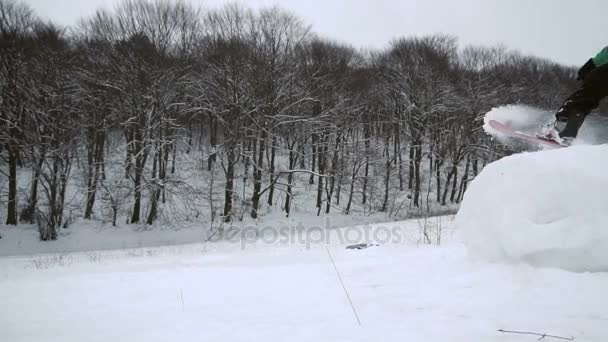 Сноубордист прыгает по снежному склону — стоковое видео