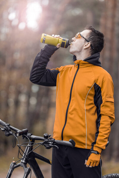 Байкер пьет воду из бутылки
