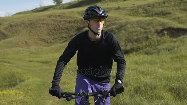 Hombre montando bicicleta hasta montaña hierba colina — Vídeos de Stock