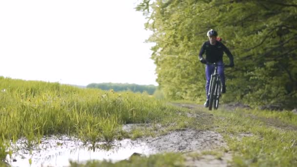 Mochilero hombre paseos bicicleta en el bosque charco piscina — Vídeos de Stock