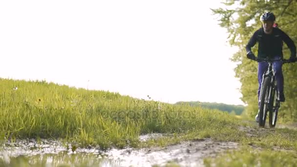 Zaino uomo cavalca bicicletta nella piscina pozzanghera foresta — Video Stock