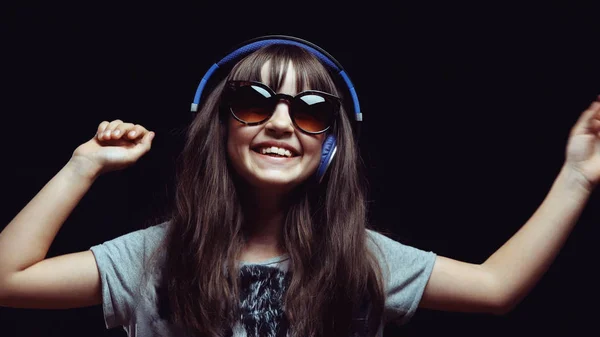 Menina bonito jovem com fones de ouvido e óculos de sol — Fotografia de Stock