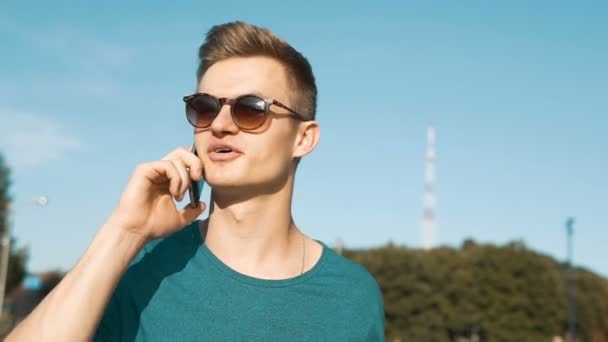 Hombre lleva gafas de sol hablando de teléfono — Vídeos de Stock