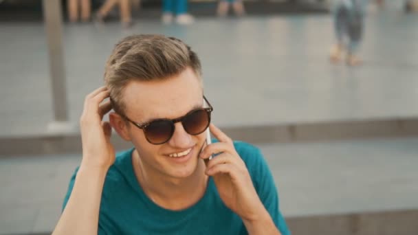 Человек, сидящий на лестнице и разговаривающий по телефону — стоковое видео