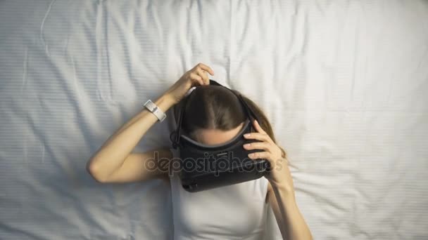 Девушка надевает очки VR на кровать — стоковое видео