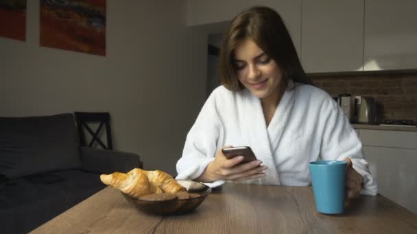 Chica bebe café y utiliza Smartphone — Vídeo de stock