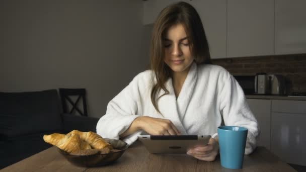 Chica feliz bebe café y utiliza la tableta — Vídeos de Stock