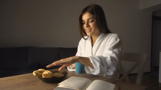 Chica lee libro mientras desayuna — Vídeos de Stock