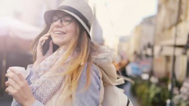 Telefon ve kahve ile gülümseyen kız yürüyor