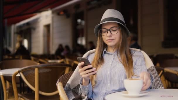 Sorrindo menina usa telefone durante o tempo de café — Vídeo de Stock