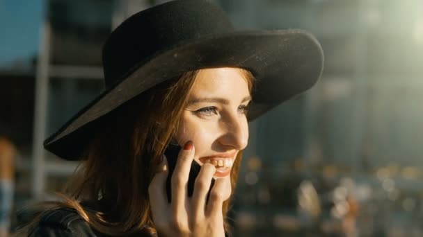 Девушка разговаривает по телефону перед современным зданием — стоковое видео