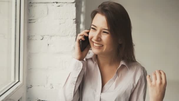 Chica ríe mientras habla por teléfono — Vídeos de Stock