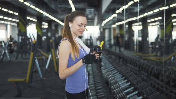 Chica teniendo descanso con el teléfono en el gimnasio — Vídeos de Stock