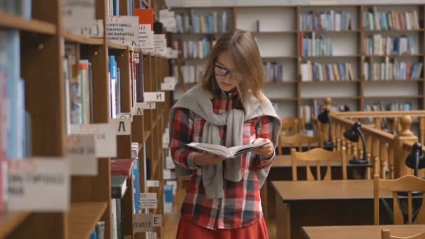 Reaing un libro in biblioteca — Video Stock