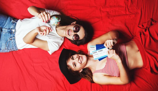 Duas meninas amigas deitadas na cama vermelha — Fotografia de Stock