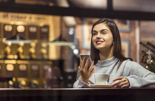 Dziewczyna trzyma telefon w Cafe — Zdjęcie stockowe