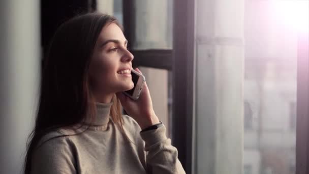 Vrouw gesprekken op telefoon in de buurt van venster — Stockvideo