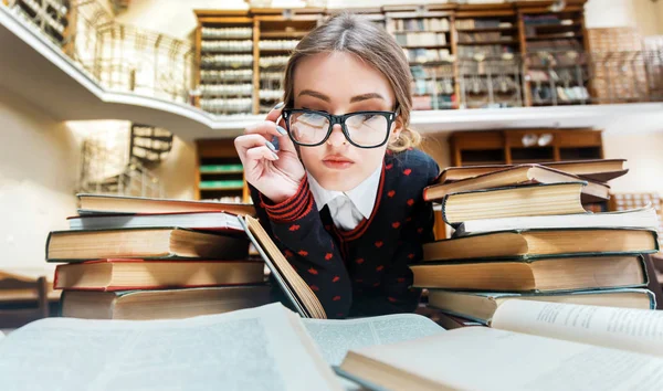 Meisje met boeken in de bibliotheek — Stockfoto