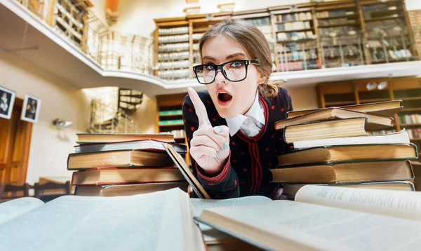 Meisje met boeken in de bibliotheek — Stockfoto