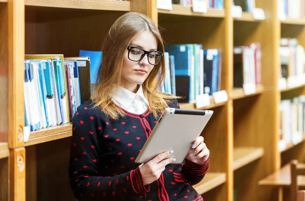 Blond meisje Tablet in bibliotheek gebruiken — Stockfoto