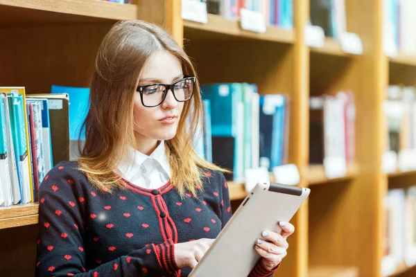 Menina loira usar Tablet na biblioteca — Fotografia de Stock