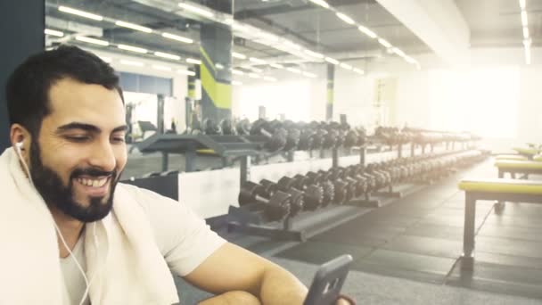 Hombre con teléfono en el gimnasio — Vídeos de Stock