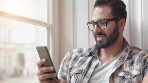 Hombre utiliza el teléfono cerca de la ventana — Vídeos de Stock