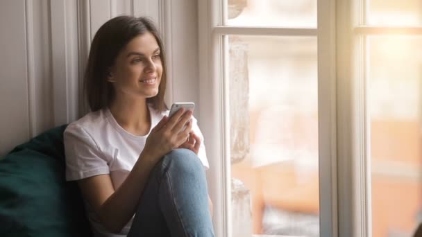 Mujer alegre utiliza Gadget cerca de la ventana — Vídeos de Stock