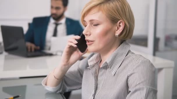 Mujer habla por teléfono en la oficina — Vídeo de stock