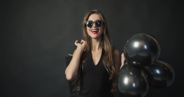 Mujer sonriente con globos negros y bolsa de compras — Vídeos de Stock