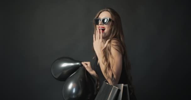 Mujer sonriente con globos negros y bolsa de compras — Vídeos de Stock