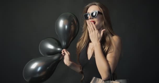 Glad kvinna med svarta ballonger och shoppingväska — Stockvideo