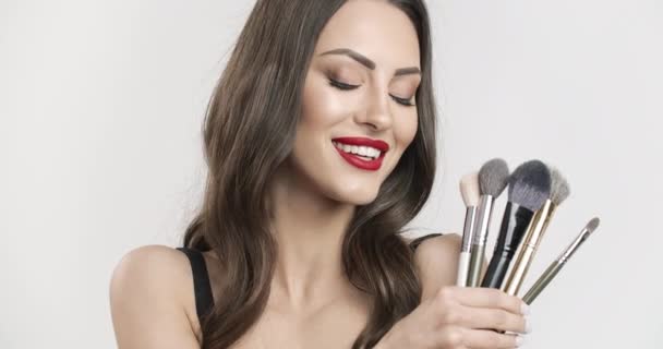 Улыбающаяся женщина с кисточками для макияжа — стоковое видео