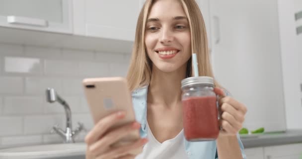 Женщина со смартфоном пьет смузи — стоковое видео